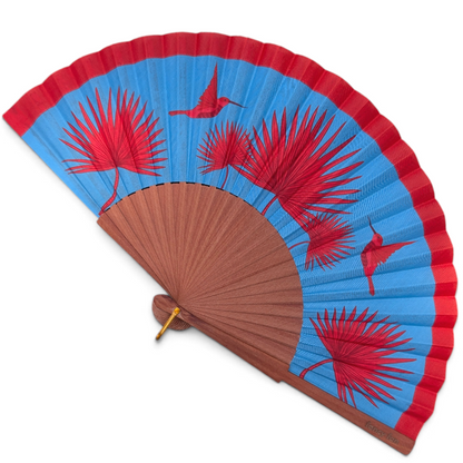 LE BAZAR INOUI Faltfächer mit blauem Stoff, rotem Kolibri- und Palmenprint sowie braunem Holzrahmen.